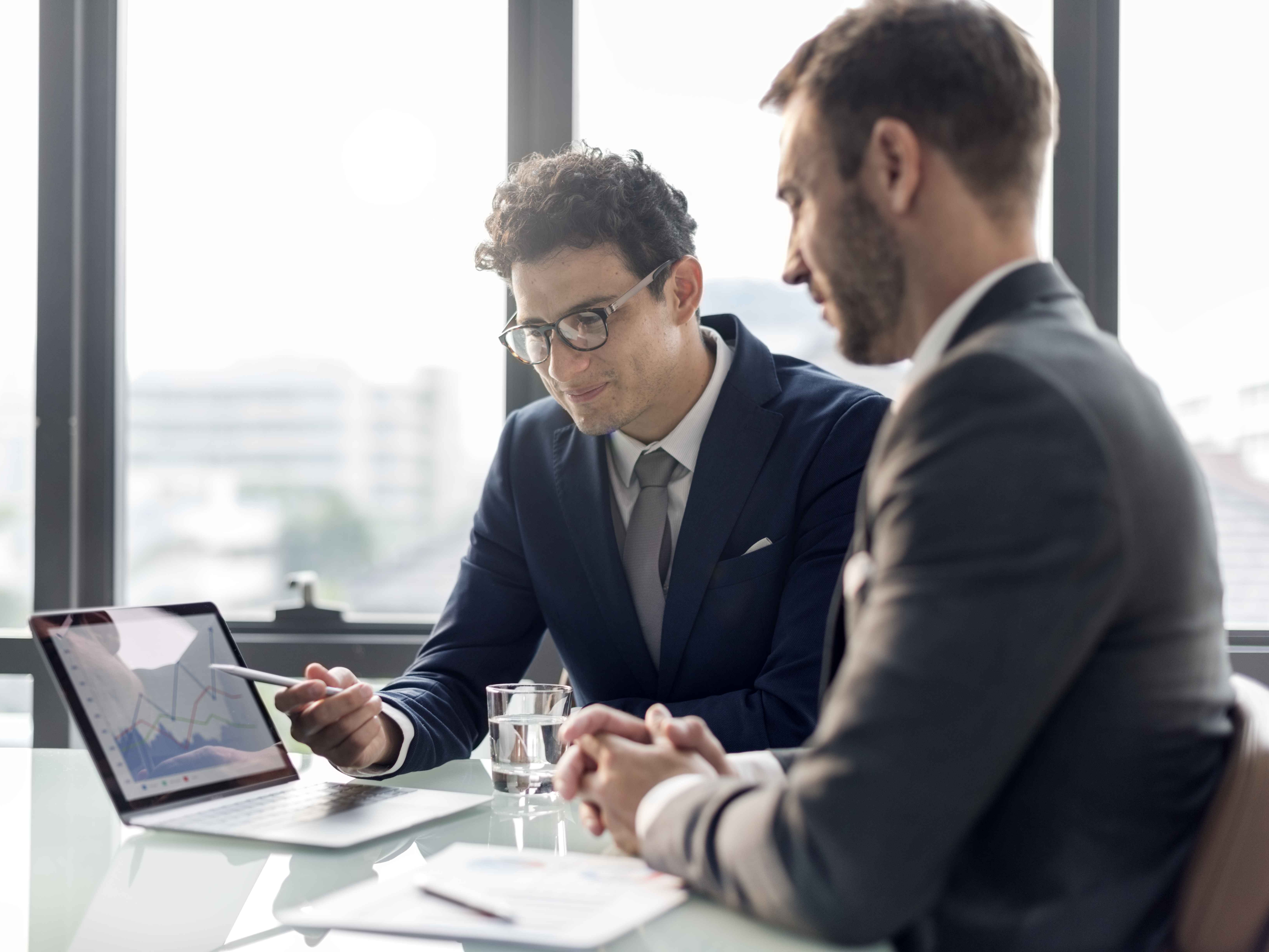 2 individuals discussing statistics on a tablet screen.